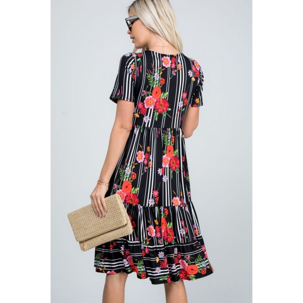 back view woman wearing black floral midi dress and holding a purse.