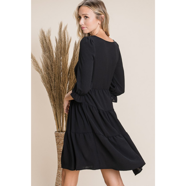 side/back view of tiered black dress with 3/4 length sleeves