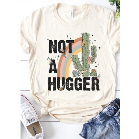 Cream colored tee with the words "not a hugger" and a cactus and rainbow image