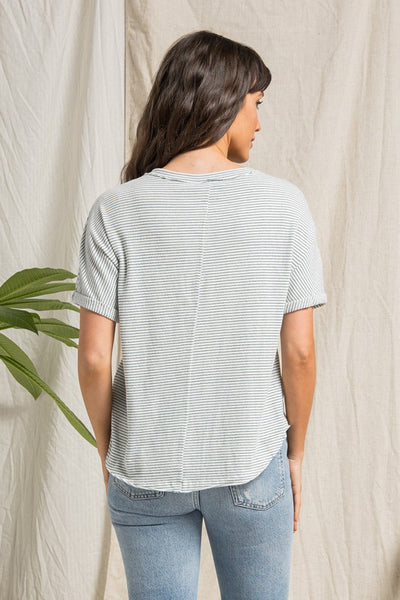 rear view of short sleeve cream top with dark teal stripes, buttons, and rolled up sleeves.