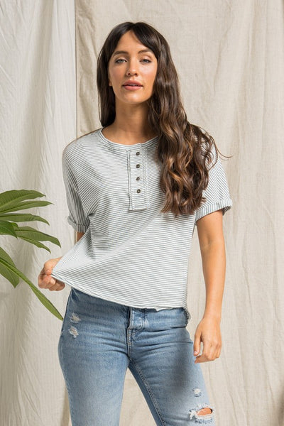 short sleeve cream top with dark teal stripes, buttons, and rolled up sleeves.