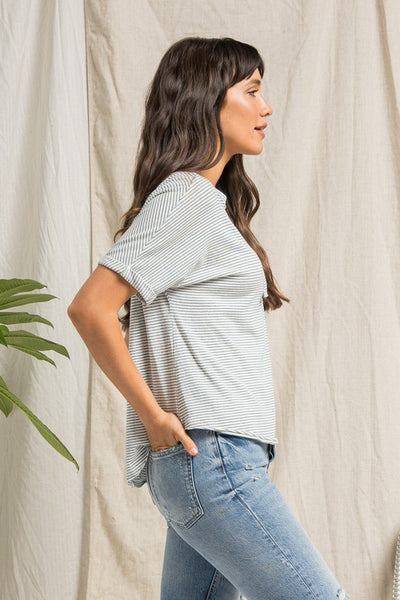 side view of short sleeve cream top with dark teal stripes, buttons, and rolled up sleeves.